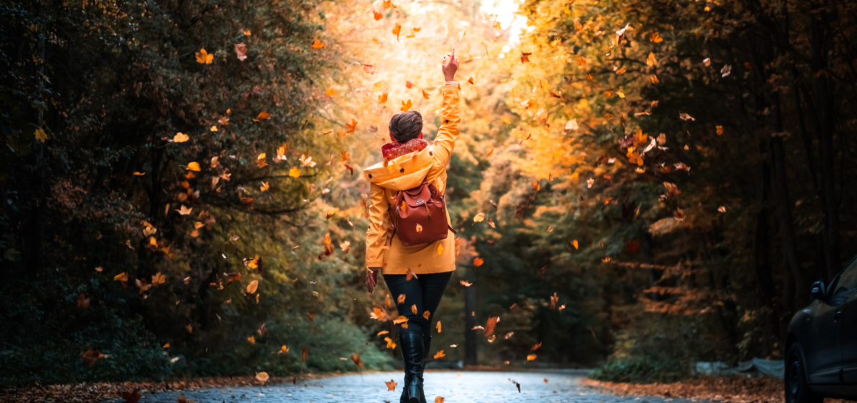 a woman walking down a road in the fall