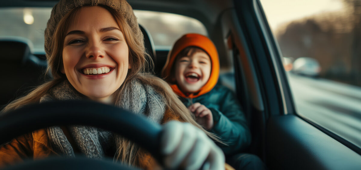 Young happy mother with driving a car with her laughing son