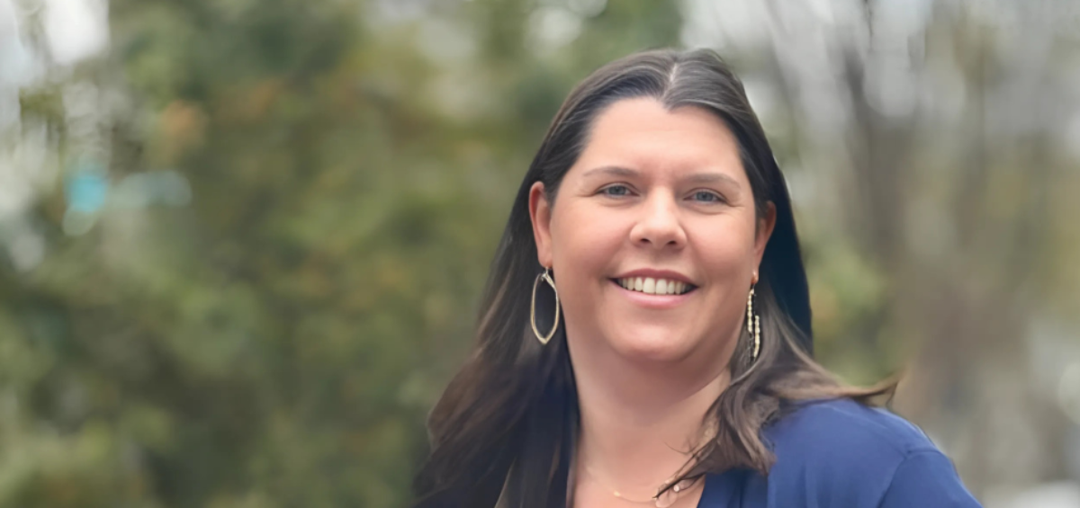 Whitney B. Altizer, smiling outdoors with blurred greenery in the background.